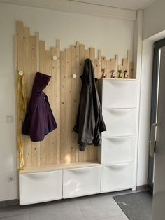 a coat rack with two coats hanging on it's sides next to a door