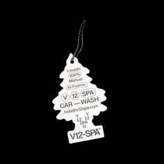 a white christmas tree ornament hanging from a black background with the words spa and car wash written on it