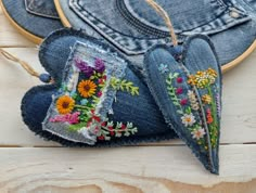 two pieces of denim with embroidered flowers on them are next to a pair of jeans