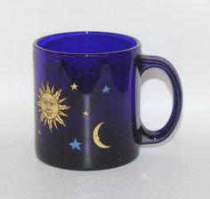 a blue coffee mug with the sun and moon painted on it's side, against a white background