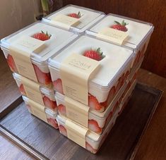 four plastic containers filled with strawberries on top of a wooden table