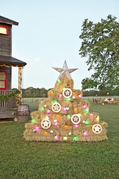 a christmas tree made out of hay with lights on it in the middle of a yard