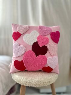 a pink pillow with hearts on it sitting on a stool