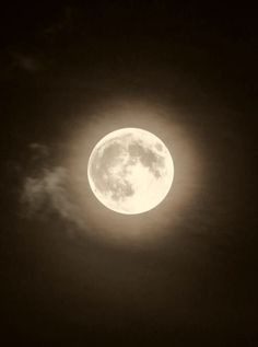 the full moon is seen through clouds in this black and white photo