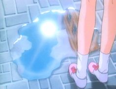 the legs and feet of a person standing on a tile floor next to a puddle