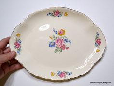 a hand is holding a plate with flowers on it