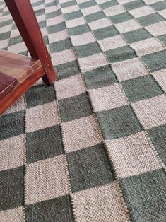 a wooden bench sitting on top of a checkered carpeted floor next to a window