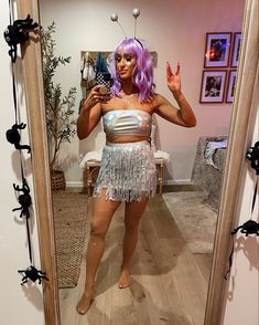 a woman with purple hair is standing in front of a mirror and taking a selfie