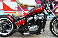 a red and black motorcycle parked in front of a graffiti covered wall