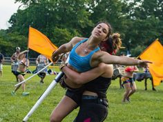 a woman holding onto another woman in the middle of a field with yellow flags behind her