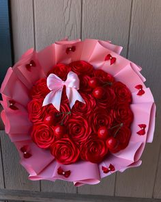 a bouquet of red roses in the shape of a heart with a bow on it