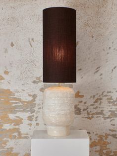 a lamp that is on top of a white block with a brown lampshade