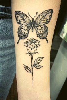 a black and white tattoo with a butterfly on it's arm next to a rose