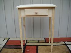 a small wooden table sitting on top of a carpeted floor next to a wall