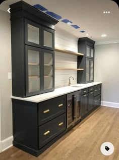 an empty kitchen with black cabinets and white counter tops, wood flooring and wooden floors