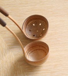 two wooden spoons with holes in them on a table