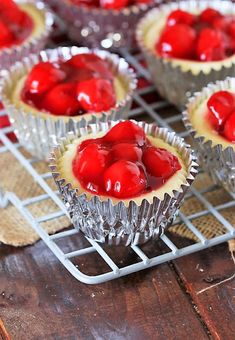 small cupcakes with cherries on top sitting on a cooling rack, ready to be eaten