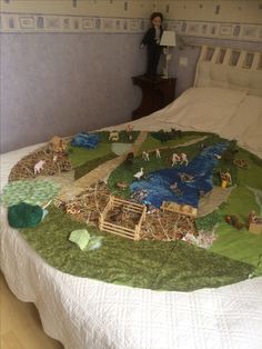 a bed with a white bedspread covered in toy farm animals and trees on it