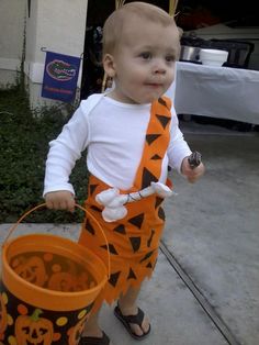 a toddler dressed up as a tigger holding a trick or treat bucket