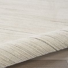 a close up view of a white rug on a wooden floor, with the top part of the rug visible