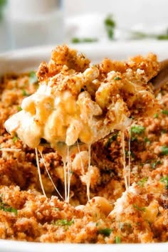 a spoon full of macaroni and cheese being lifted from a casserole dish