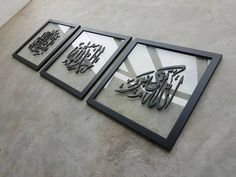 three framed art pieces on the side of a building with arabic writing in black and white