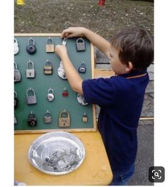 a young boy is playing with some padlocks on a green and yellow table