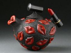 a black and red teapot with lipstick on it