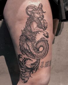 a black and white photo of a dragon tattoo on the leg, with words written below it