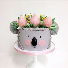 a cake decorated to look like a koala bear with pink flowers on its head