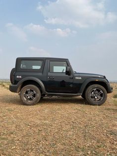 a black jeep parked in the middle of a dry grass field on a sunny day