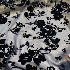 black flowers on white sheer fabric being held by someone's hand