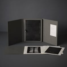 an open book with black and white images on the cover is sitting in front of a gray background