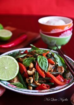 a plate full of vegetables and chopsticks on a table next to a bowl