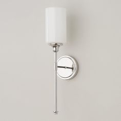 a wall mounted light with a white shade on it's arm and the bulb turned off