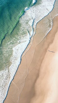 an aerial view of the ocean and beach with waves coming in from the water,