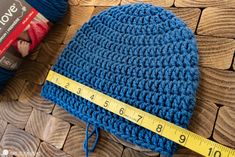 a blue crocheted hat with a measuring tape next to it