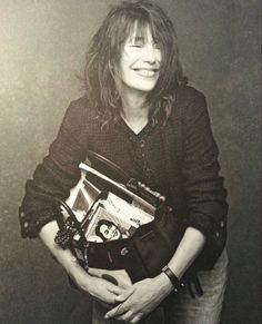 a woman is holding an open purse and smiling at the camera while posing for a black and white photo