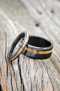 two wedding rings with black and yellow wood inlays