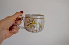 a hand holding a coffee cup with flowers painted on it