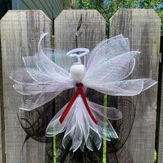 a white and red bow on top of a wooden fence next to a green bush