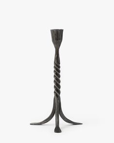 a tall metal candle holder with spiral designs on the top and bottom, against a white background