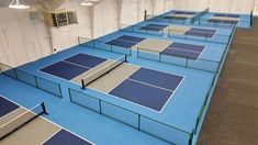 several tennis courts are lined up in the middle of an indoor court with blue and gray surfaces