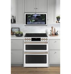 a white stove top oven sitting in a kitchen under a tv mounted on the wall