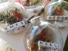 christmas ornaments with words written on them and pine cones in the middle, sitting on a table