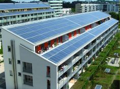 an aerial view of a building with solar panels on it's roof and the surrounding buildings