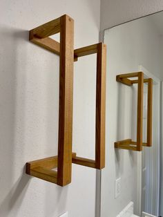 two wooden shelves mounted to the side of a white wall next to a bathroom mirror