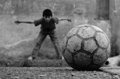 two boys playing with a soccer ball on the ground