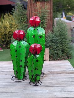 three green cactus sculptures sitting on top of a wooden table