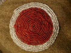 a red and white beaded basket sitting on top of a brown table next to a rug